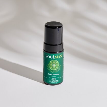 Close-up of a green spray bottle with a black cap on a white surface, label reads Soulman Lakshmi Soul Mousse.